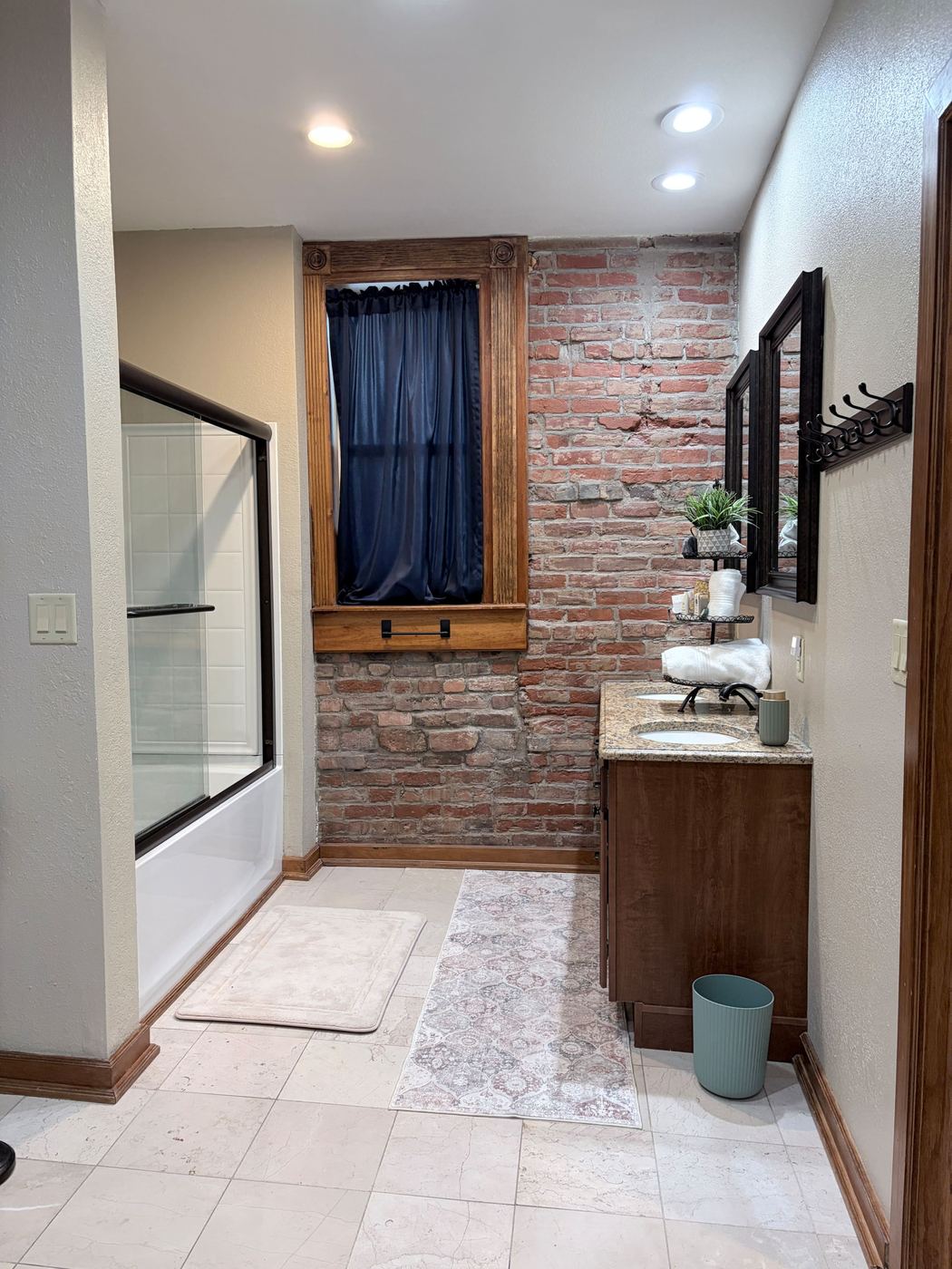 Bathroom with a tub and shower, double vanity, and a brick accent wall